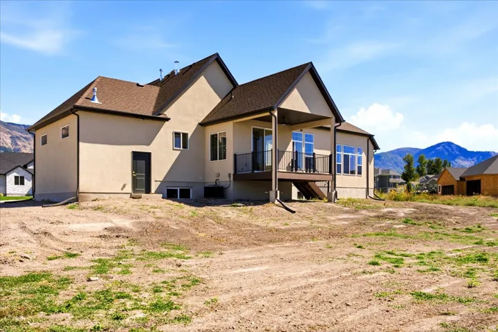 Two-story stucco exterior with a covered deck and dark brown railings