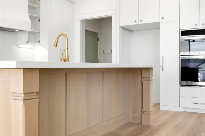 Kitchen island with wood-finish paneling, light-toned countertop, and a gold-finish gooseneck faucet