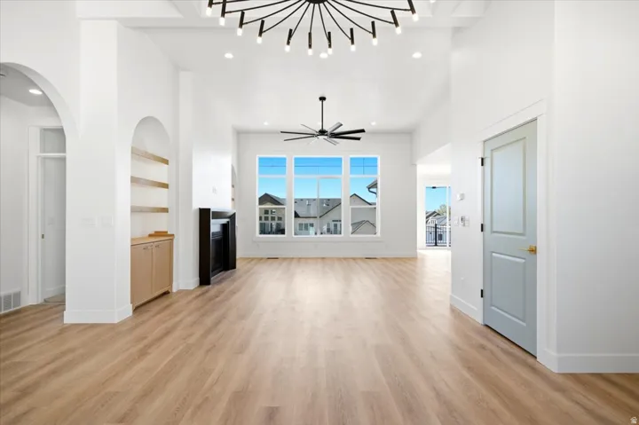 Vaulted ceilings, wood-finish flooring, built-in shelving, large multi-pane windows, and a black chandelier