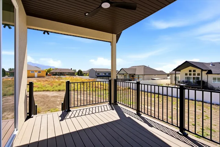 Covered outdoor deck with composite decking, black metal railings, and a built-in ceiling fan