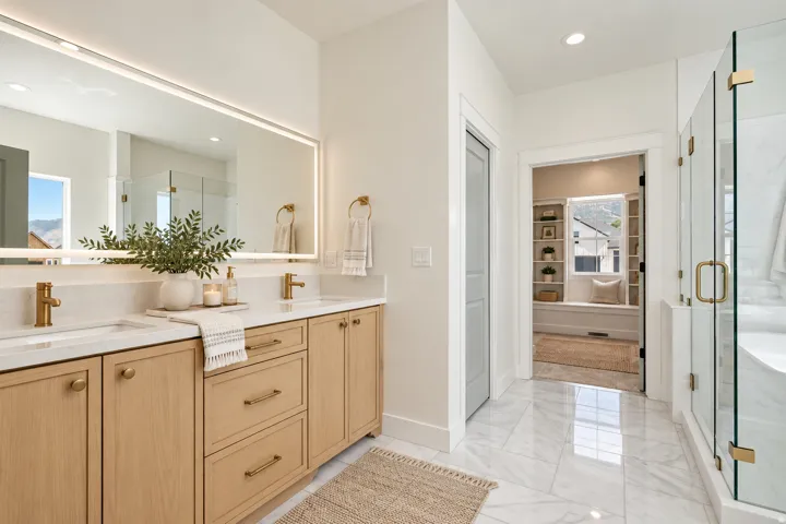 Digitally staged. Primary ensuite bathroom. Dual vanity with light wood-finish cabinetry, white countertops, and gold-tone fixtures