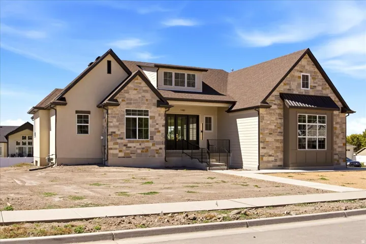 Stucco and stone exterior with a gabled roofline, double entry doors, and a bay window