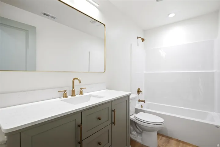 Bathroom featuring a light-colored vanity with a white countertop, an undermount sink, and brass fixtures