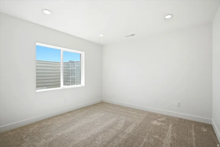 Recessed ceiling lighting, white walls, and carpet flooring