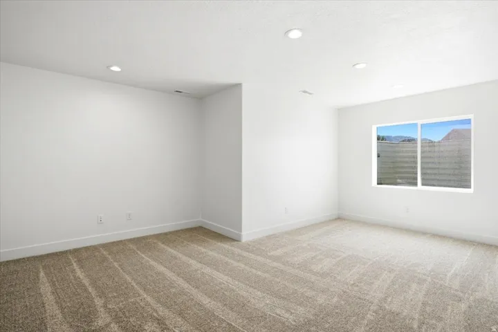 Recessed ceiling lighting, crisp white walls, and neutral-toned carpeting