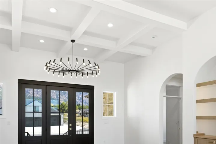 White coffered ceiling with recessed lighting and a central chandelier