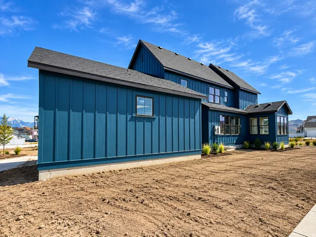 Blue vertical siding exterior with multiple pitched roofs, dark-framed windows, and a concrete foundation