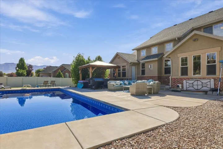 Backyard oasis featuring an in-ground swimming pool, extensive concrete patio, and a wooden gazebo