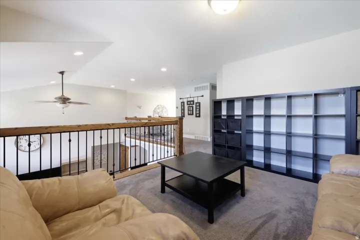 Open loft area featuring vaulted ceilings, recessed lighting, a ceiling fan, and a wood and wrought iron railing