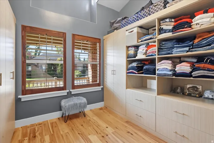Custom built-in closet system, natural wood-finish flooring, recessed lighting, and dual windows with wood plantation shutters