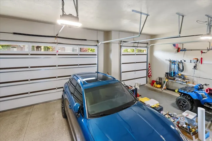 Two white garage doors with upper window panels, concrete flooring, and overhead lighting