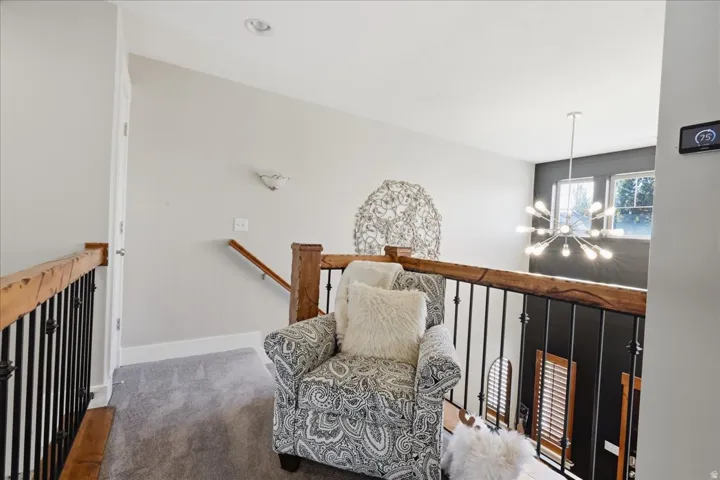 Upper-level landing featuring wood-finish handrails with wrought iron balusters, recessed lighting, and carpeting