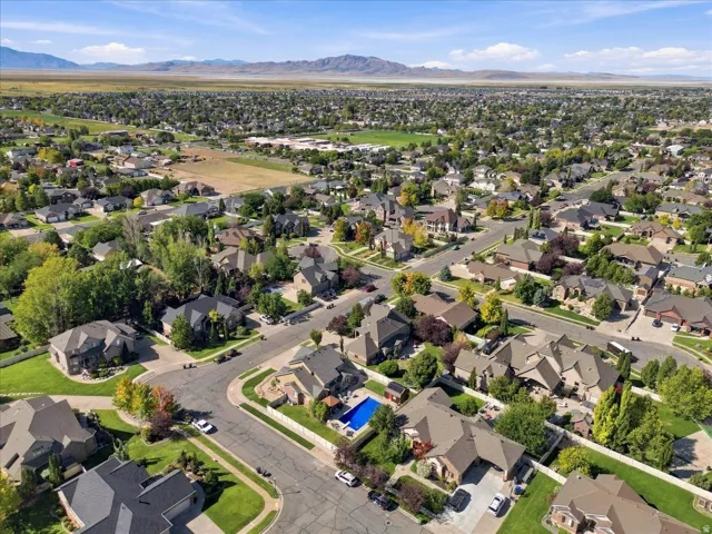 Expansive residential area featuring diverse home styles, mature landscaping, paved streets, and distant mountain ranges
