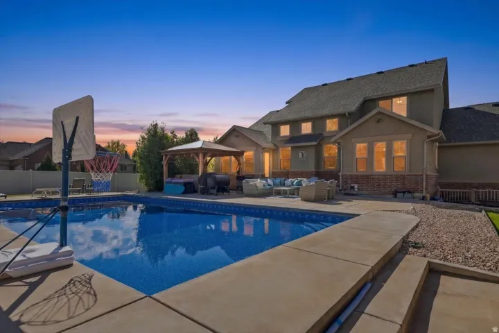 Expansive backyard with a swimming pool, concrete patio, and a dedicated outdoor seating area with a gazebo