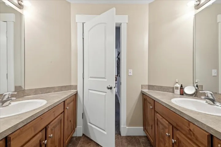 Dual vanities with integrated sinks, wood-finish cabinetry, and neutral-toned countertops