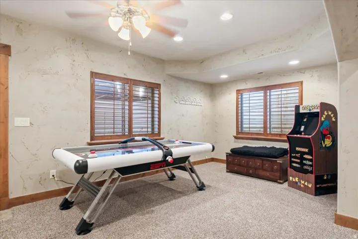 Textured walls with wooden trim, wood-framed windows featuring horizontal slat blinds, recessed lighting, and a ceiling fan with light fixture