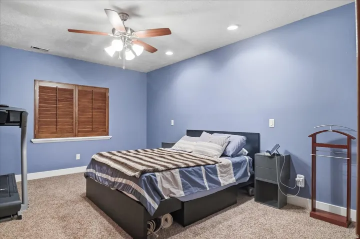Window with wood shutters, overhead ceiling fan with lighting, recessed lighting, and carpeted flooring