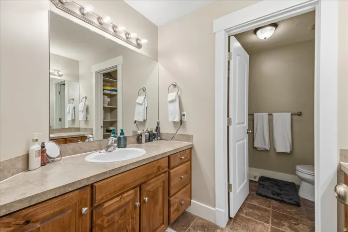 Bathroom featuring a wood-finish vanity with an integrated sink, a rectangular mirror, and an overhead vanity light bar