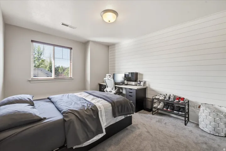 Light gray carpeting, a single window with blinds, and a white shiplap accent wall