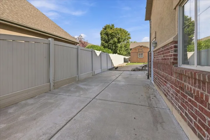 Concrete walkway alongside a property featuring a brick and stucco exterior, a window, and an exterior light fixture