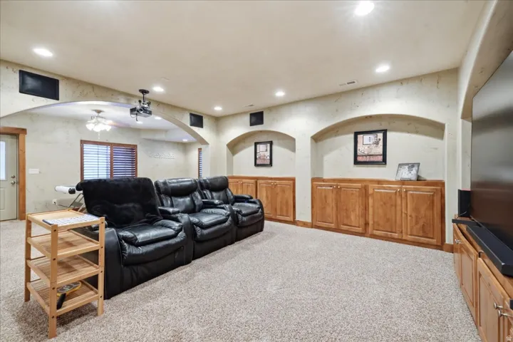 Recessed lighting, wood-finish cabinetry, built-in shelving, arched wall openings, and light-toned carpeting
