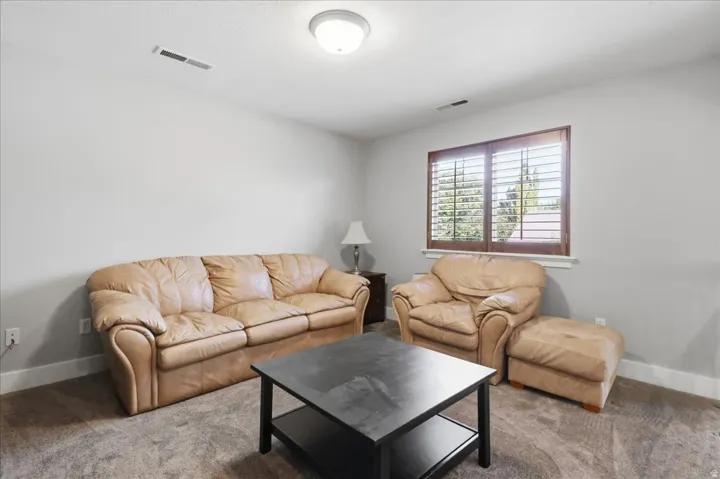 Carpeted room featuring a window with wood-finish plantation shutters, white trim, and light gray walls