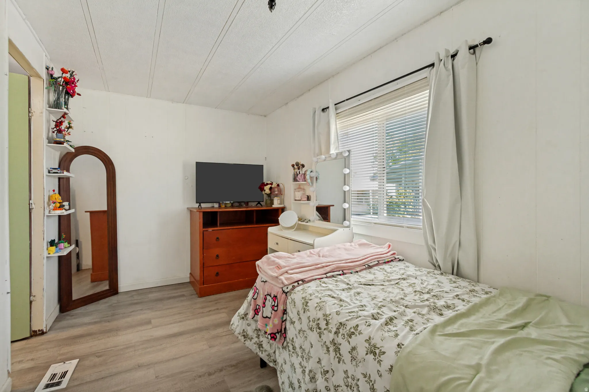 Wood-finish flooring, white paneled walls, and a large window with blinds