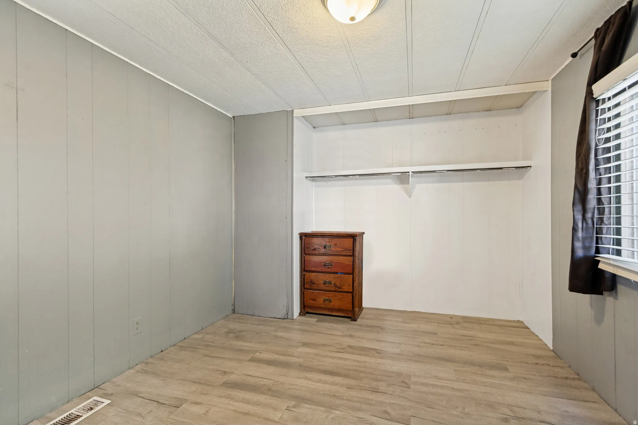 Wood-finish flooring, paneled wall finishes, built-in shelving, and a flush mount ceiling light fixture