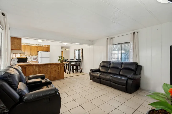 Tiled flooring throughout, kitchen with wood cabinetry and white appliances, and a window for natural light