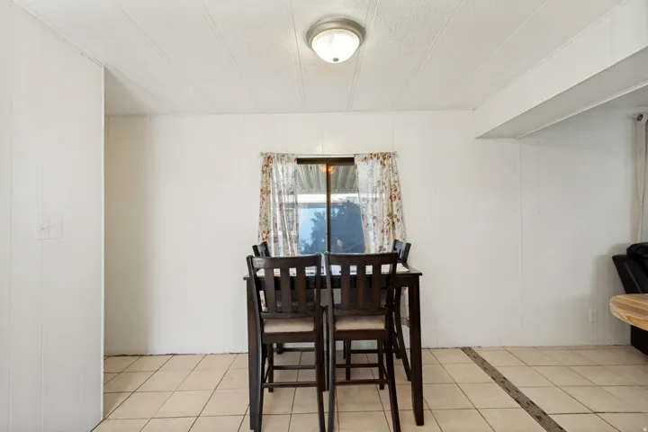 Recessed ceiling light fixture, white paneled walls, window with trim, tiled flooring
