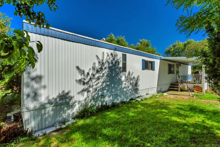 White siding with blue trim, covered porch entry, and a grassy outdoor area