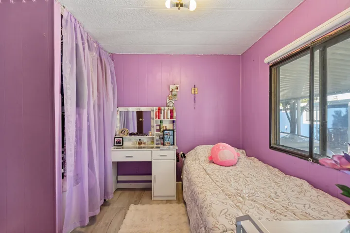 Paneling walls, wood-finish flooring, and a large window with roller shades