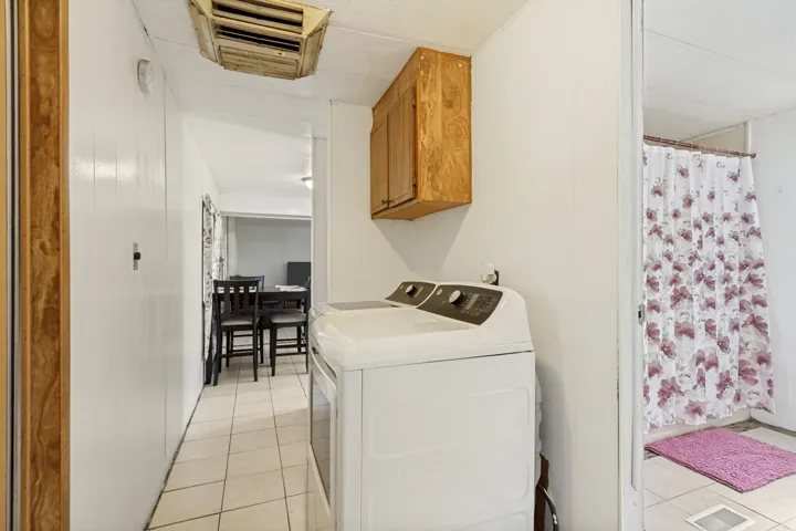 White paneled walls, wood-finish wall cabinet, and tile flooring