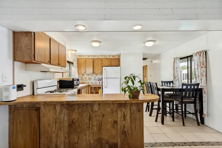 Kitchen featuring wood-finish cabinetry, a breakfast bar with a wood-finish countertop, and white appliances