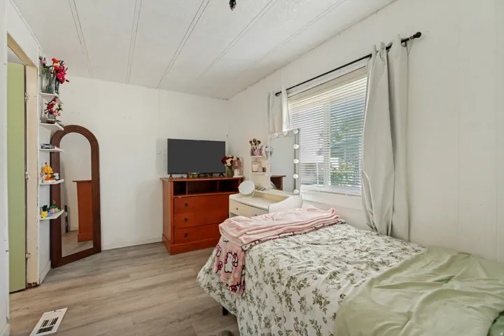 Wood-finish flooring, white paneled walls, and a large window with blinds