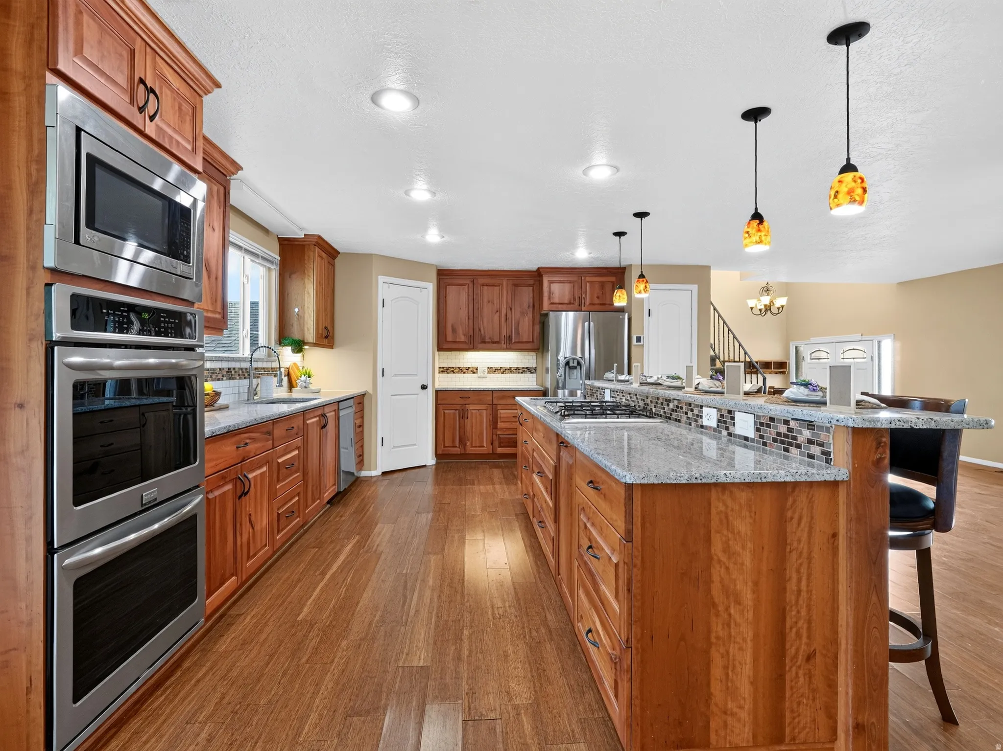 Kitchen featuring wood-finish flooring, recessed lighting, and a multi-level island with a built-in cooktop