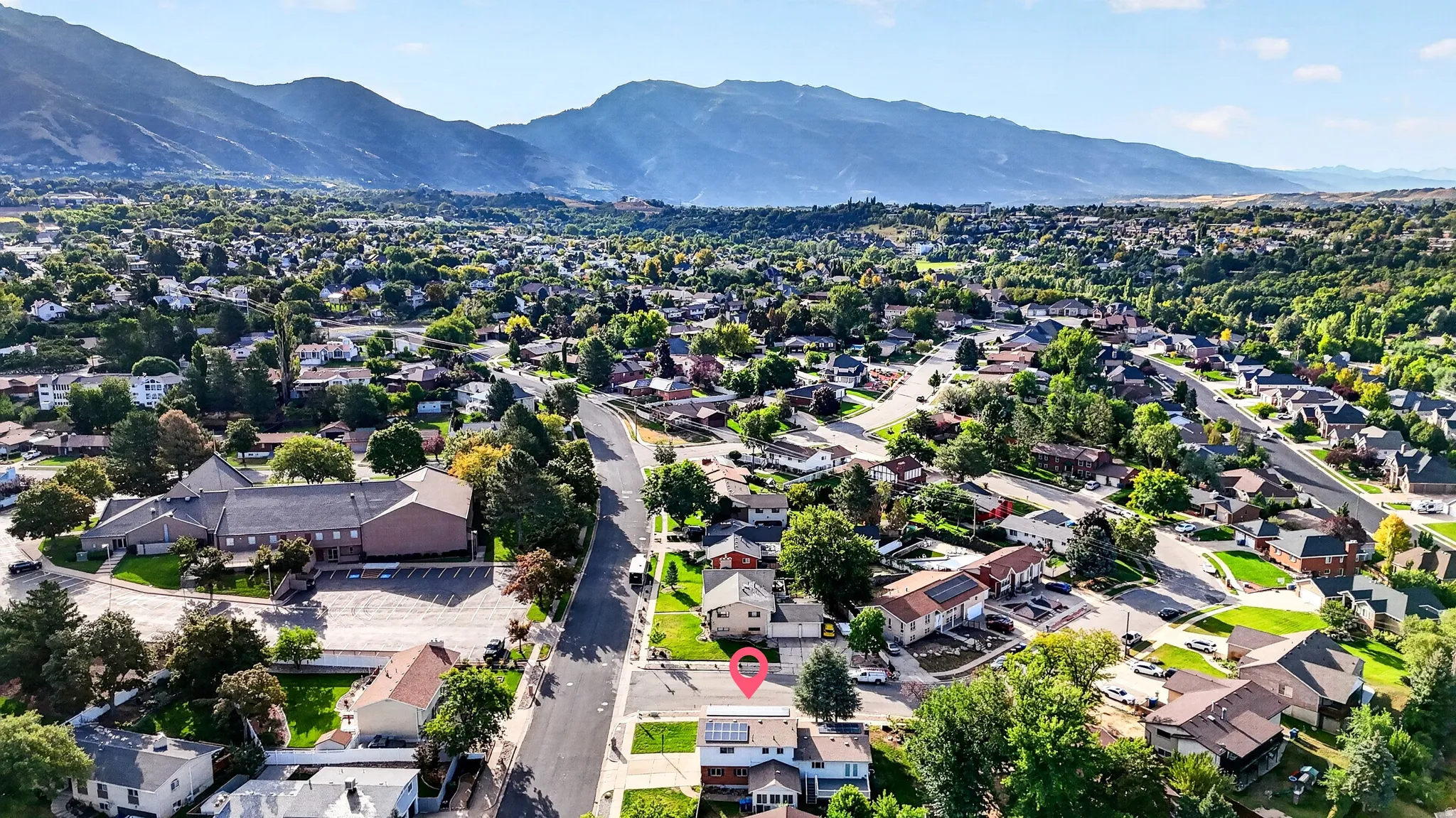 Residential neighborhood with mature trees, mountain backdrop, and clear sky