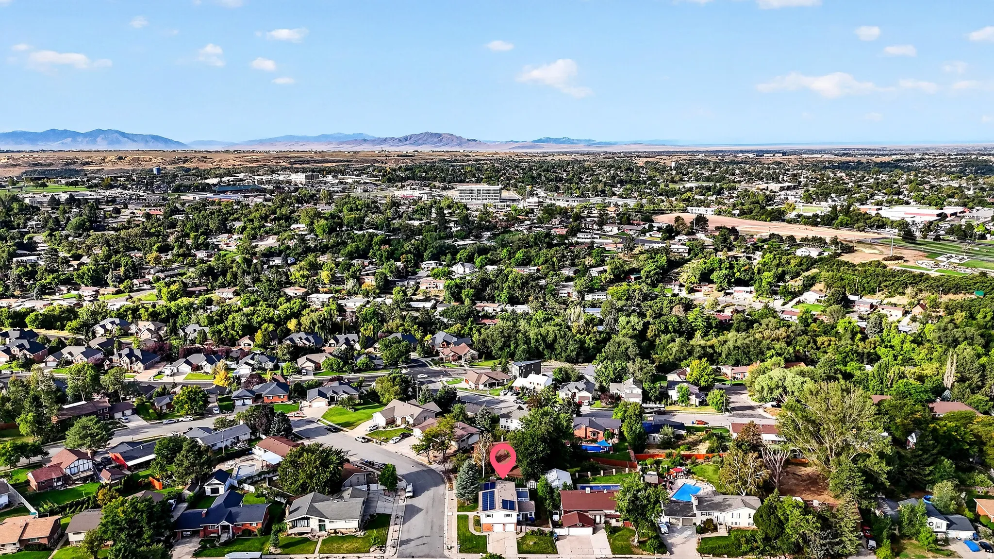 Aerial perspective of a residential neighborhood with mature trees and mountain backdrop