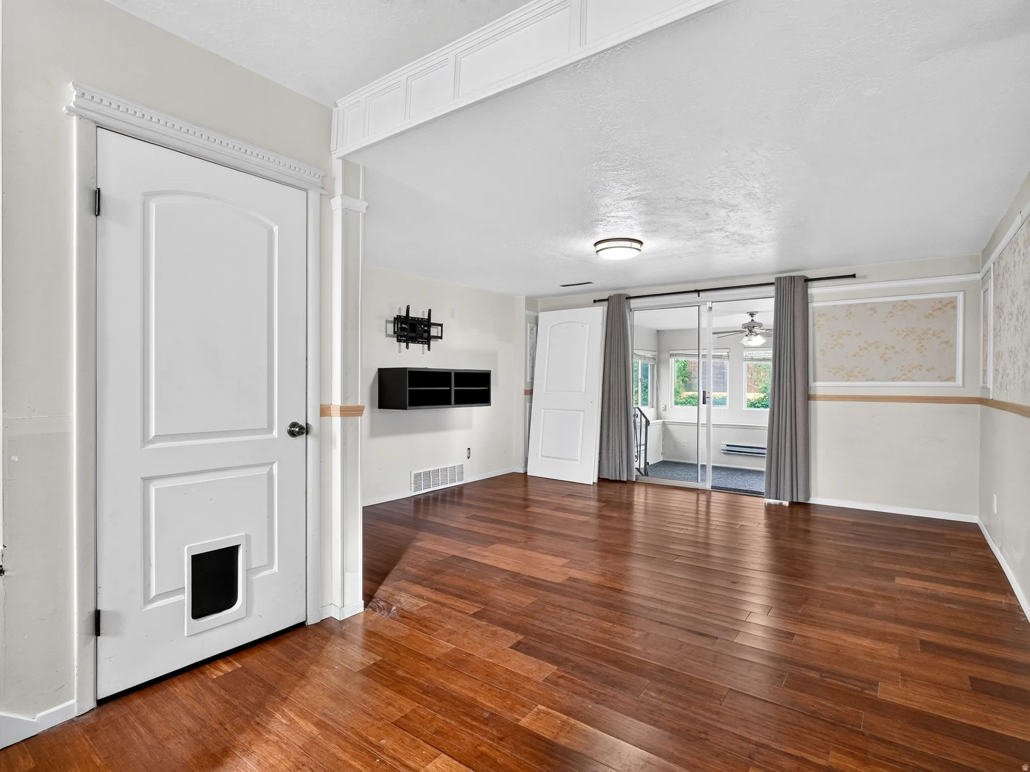 Wood-finish flooring throughout, featuring a multi-panel interior door with decorative trim and a built-in pet door
