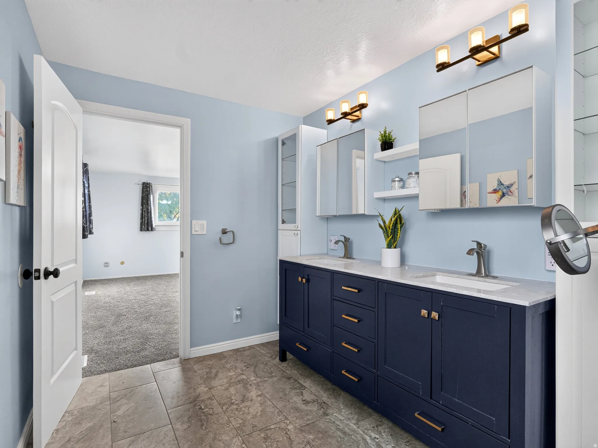 Dual vanity with undermount sinks, stone countertops, and dark cabinetry