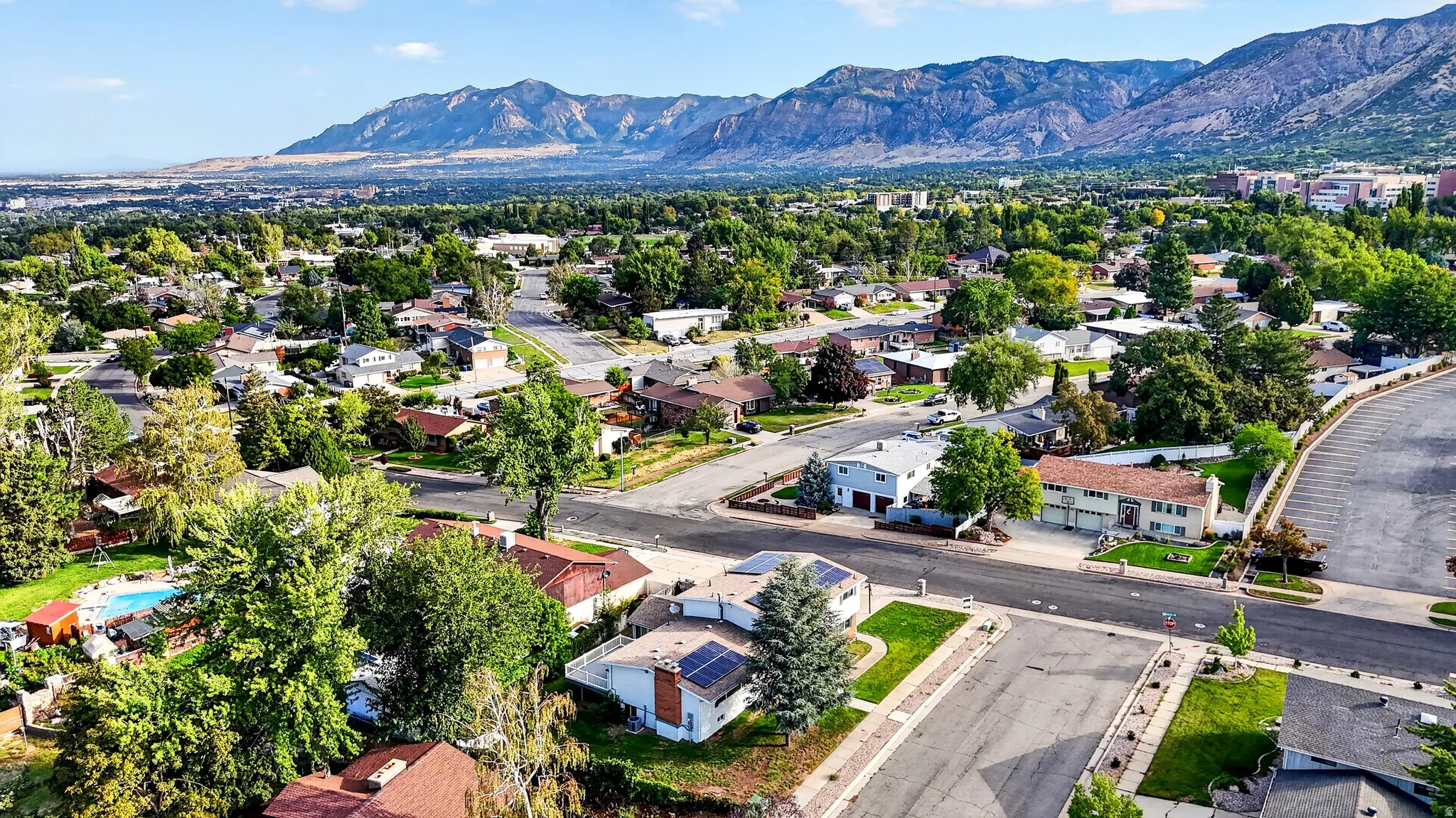 Residential neighborhood with mature trees, mountain backdrop, and varying roof styles