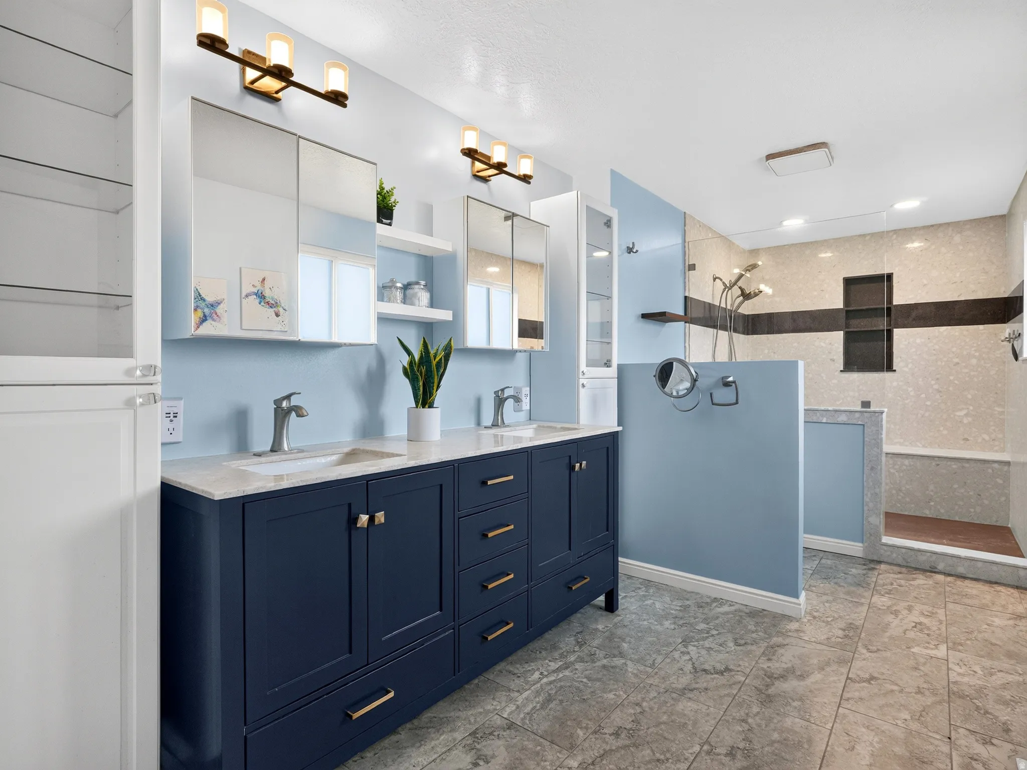 Dual vanity with undermount sinks, stone countertops, and dark blue cabinetry