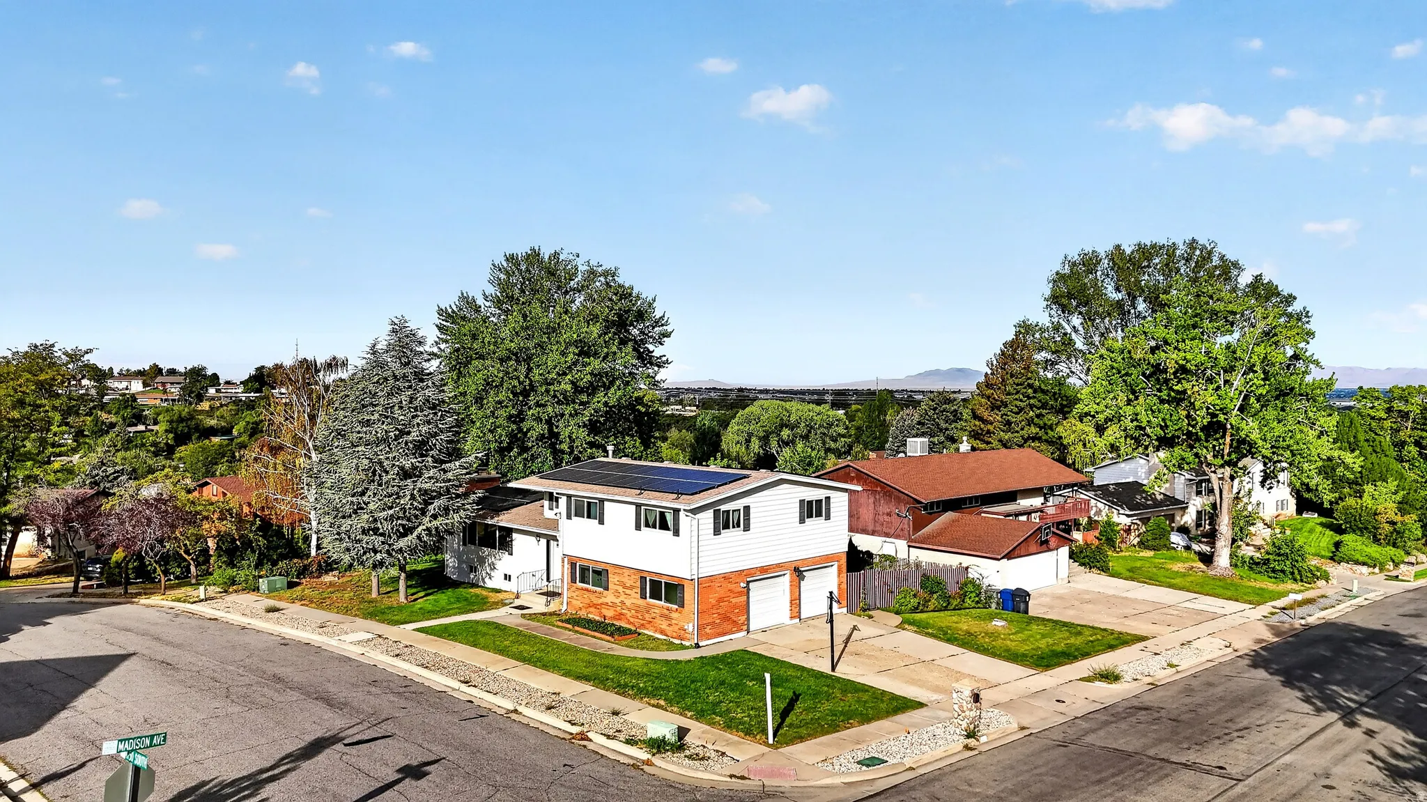 Two-story residence featuring a brick and siding exterior, solar panels, and an attached two-car garage