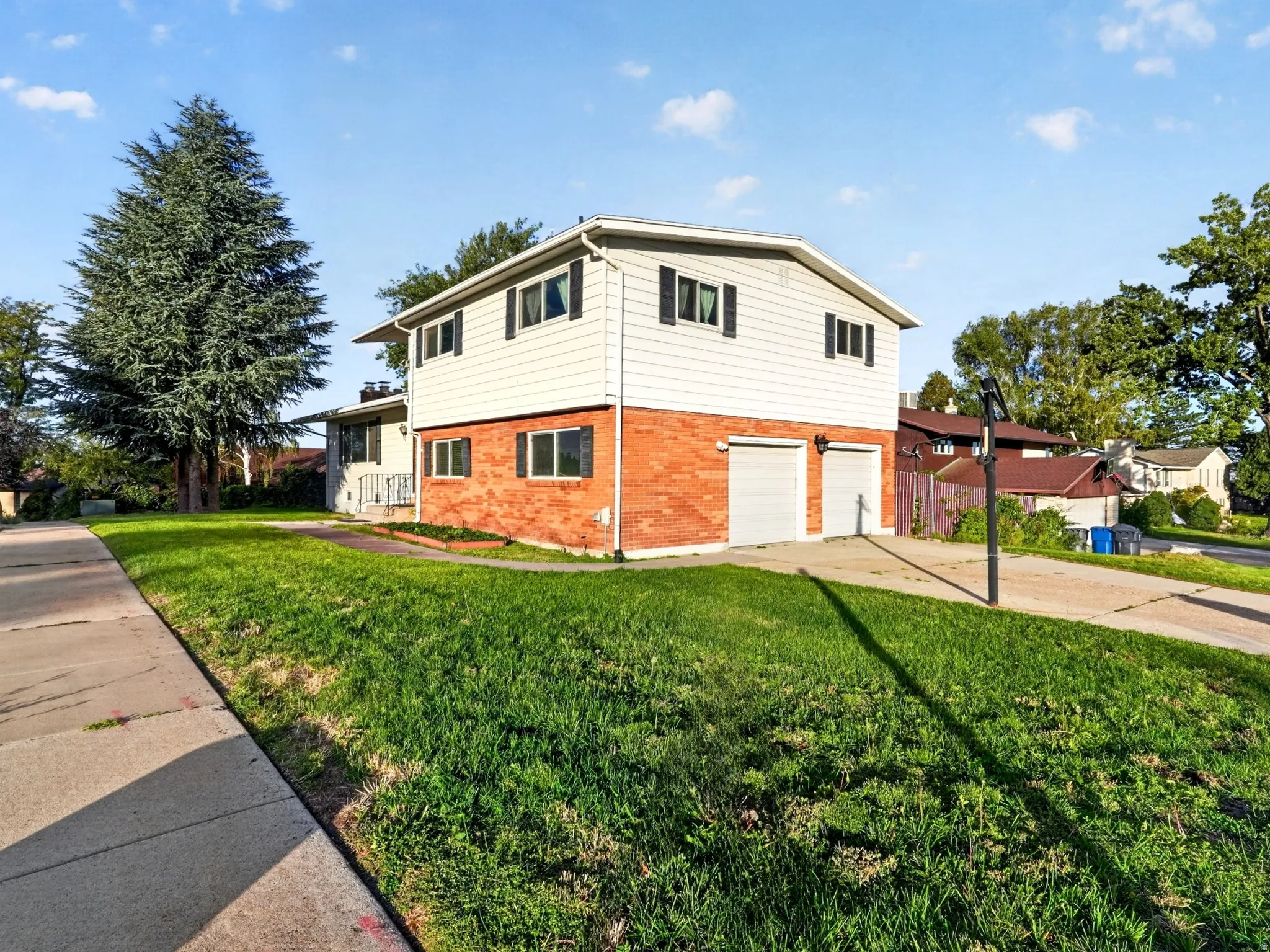 Brick and siding exterior with dark window shutters, an attached two-car garage, and a concrete driveway