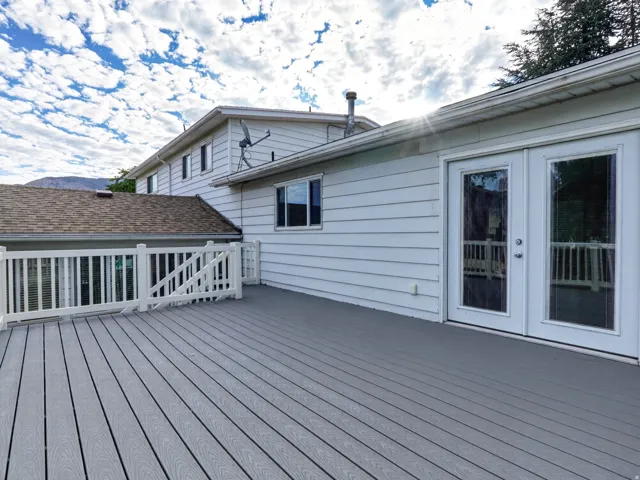 Expansive grey composite decking with white railings and double glass-paneled patio doors