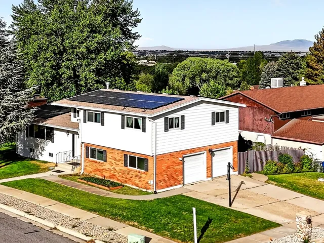 Two-story residence with brick and siding facade, solar panels, and a two-car garage