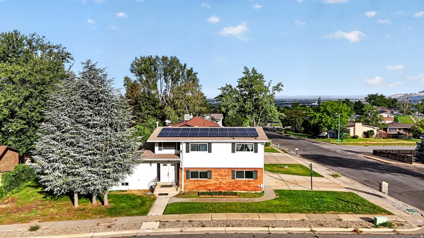 Two-story residence featuring a brick and siding exterior, front yard landscaping, a concrete walkway, and rooftop solar panels