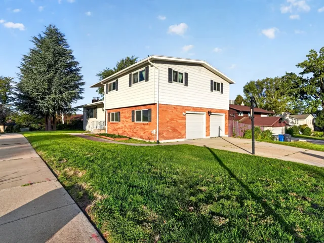 Exterior featuring a split-level design, brick and siding facade, two garage doors, and a concrete driveway