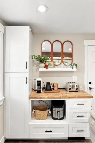 White shaker-style cabinetry with black hardware, wood-finish countertop, open shelving, recessed lighting, and wood-finish flooring