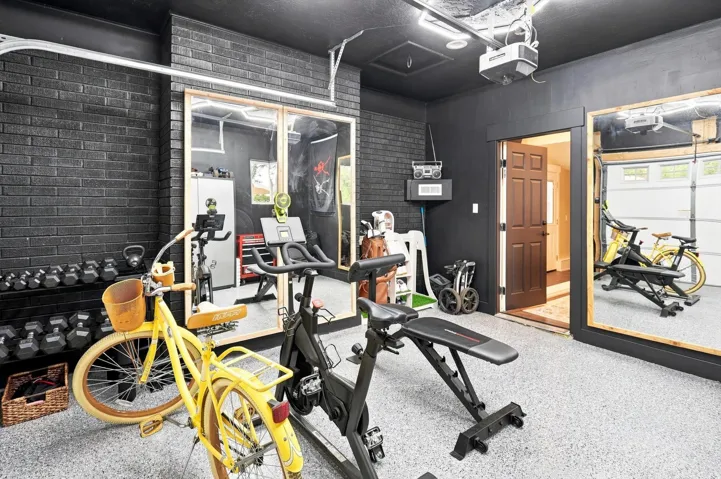 Epoxy-coated flooring, black painted brick accent wall, overhead garage door system, recessed lighting, and a paneled entry door